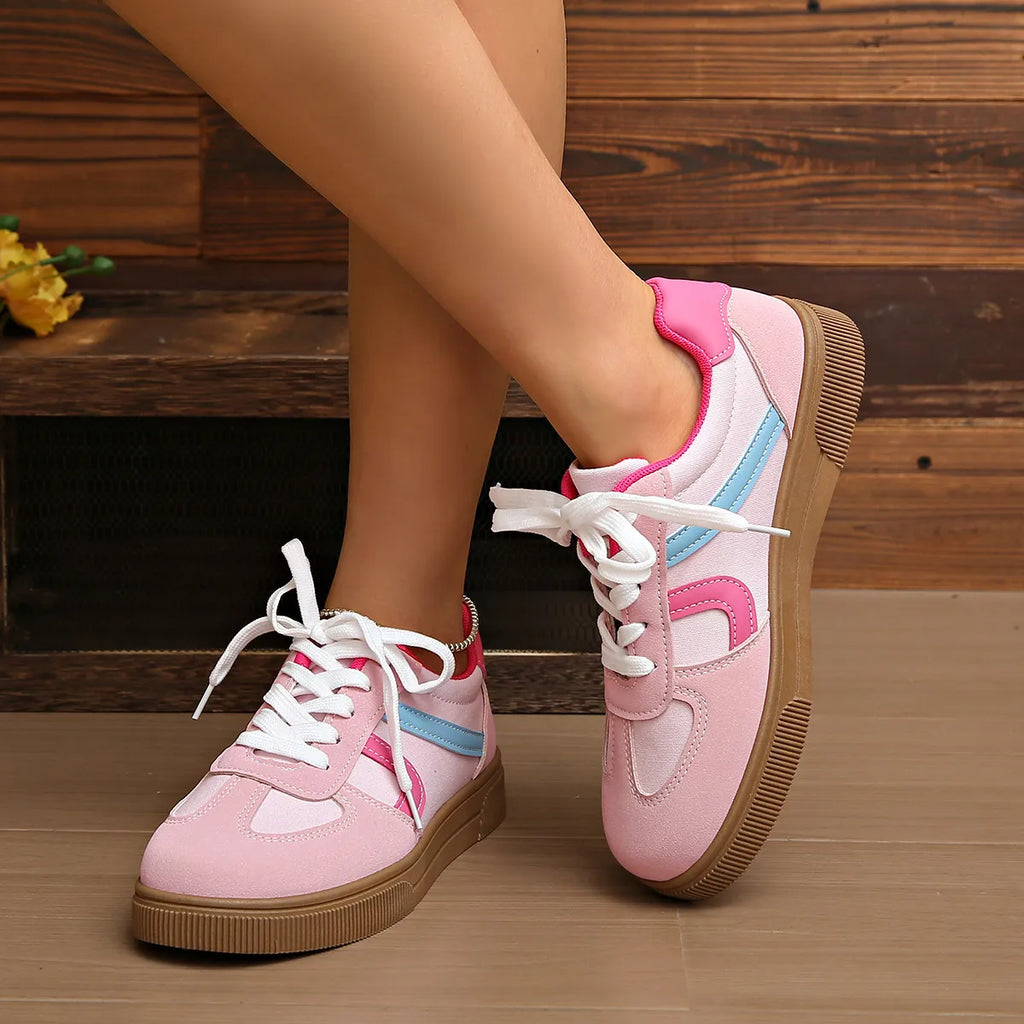 Rosa Sneaker mit weißen Schnürsenkeln, hellblauen Streifen und brauner Gummisohle. 👟