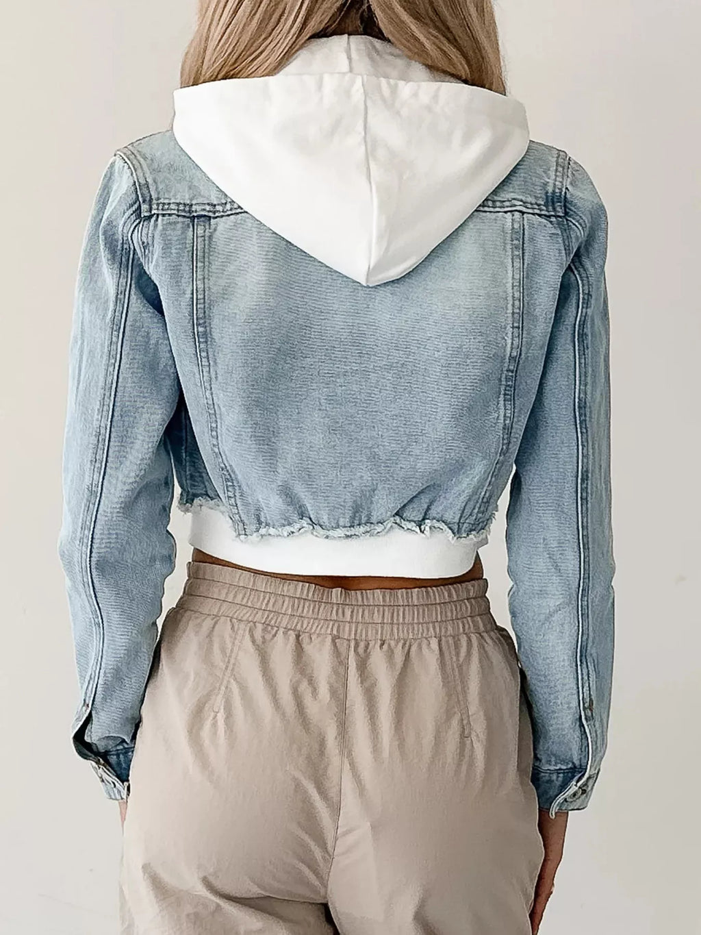 Rückansicht der Jade - Denim Jacke mit Kapuze, lässiger Cropped Schnitt in hellblau, stilvoll kombiniert mit lockeren Hosen.