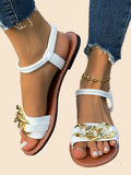 Weiße flache Sandalen mit elastischem Fersenriemen und dekorativer goldener Kettenverzierung vorne.
