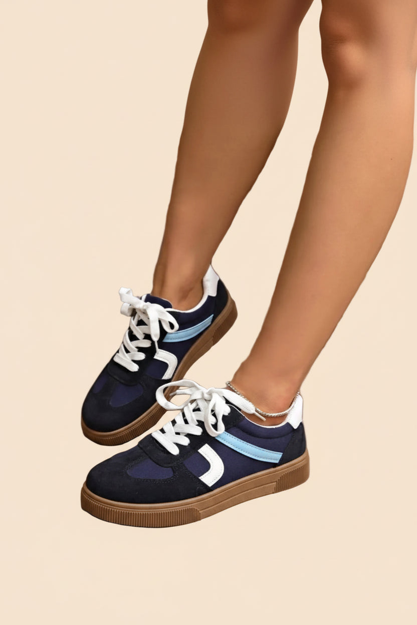 Dunkelblaue Sneaker mit weißen Schnürsenkeln, hellblauen Streifen und brauner Gummisohle. 👟