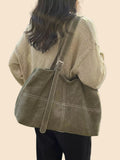 Große olivgrüne Schultertasche mit breitem Riemen, getragen über einem beigen Pullover. 👜