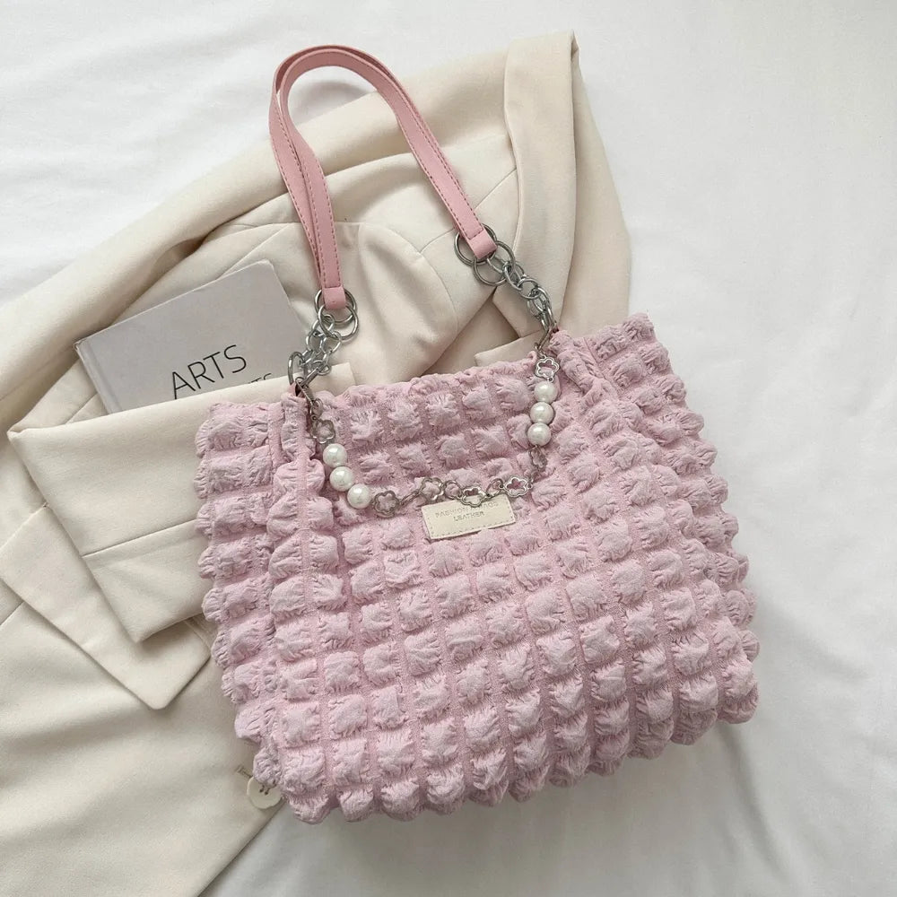 Rosafarbene Handtasche mit strukturierter Oberfläche, kurzen Trägern und dekorativer Metallkette mit Perlen