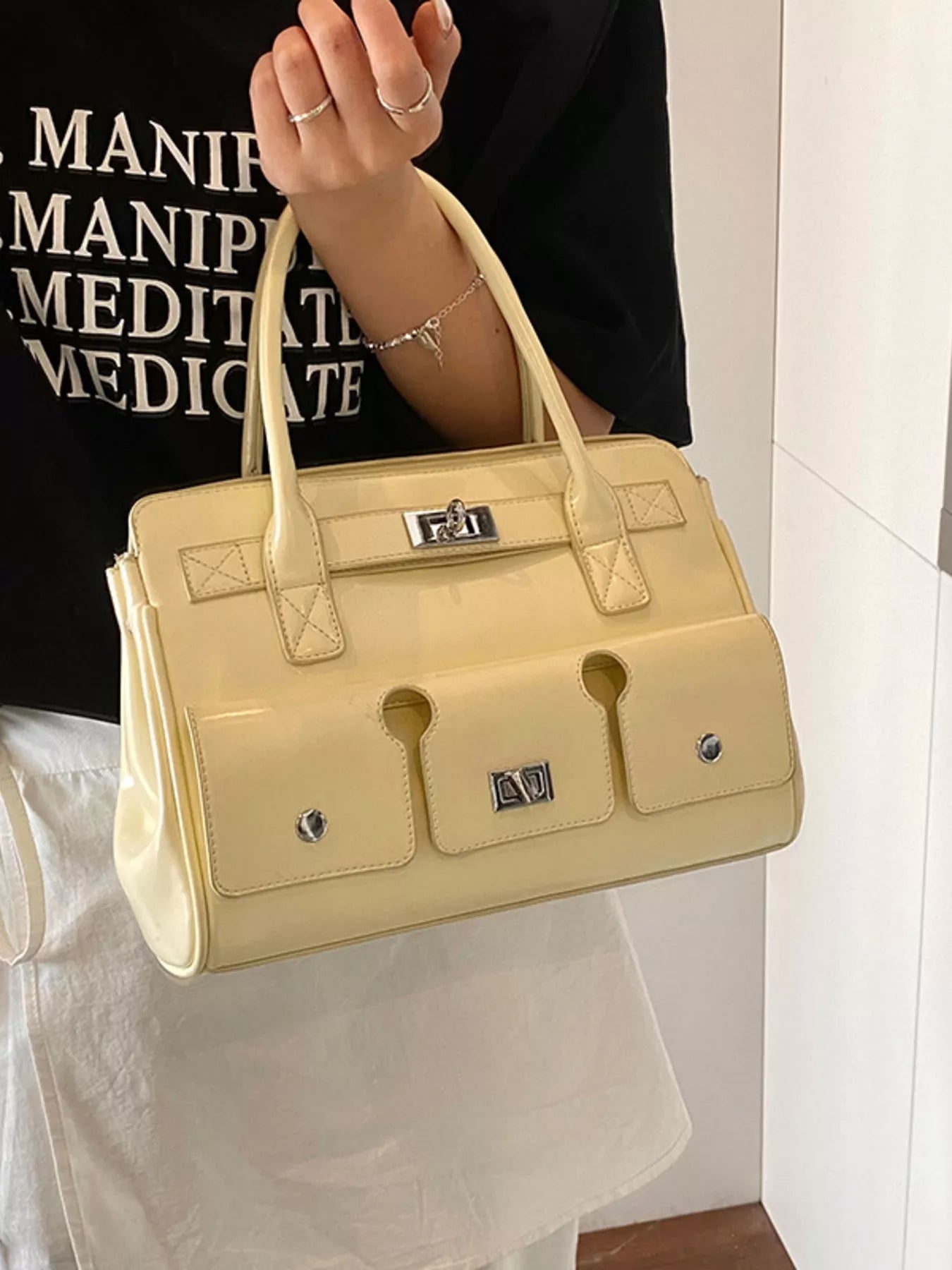 Beige Handtasche mit kurzen Tragegriffen, Fronttaschen und silbernen Verschlüssen. 👜