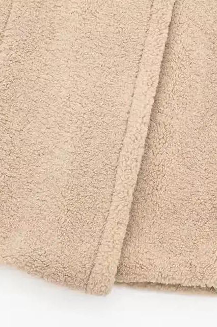 Velora Lux – Detailansicht des hochwertigen Teddyfell-Stoffs in Beige, weiche und warme Materialstruktur. 

