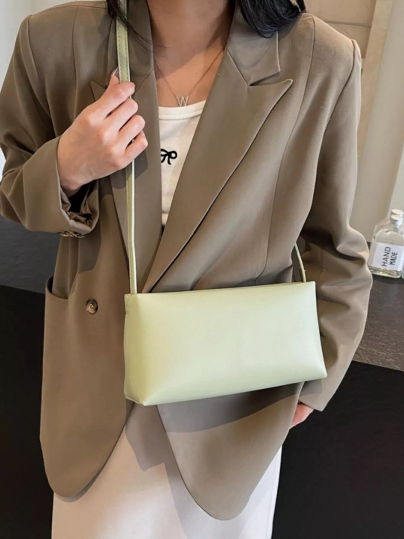 Schmale hellgrüne Schultertasche mit glatter Oberfläche und verstellbarem Riemen mit Schnalle