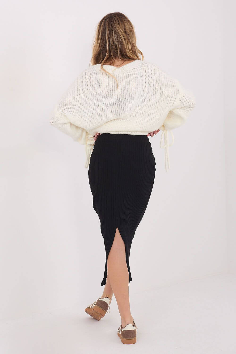 Eleganter schwarzer Damen-Strickrock in Midi-Länge kombiniert mit einem weißen Oberteil.