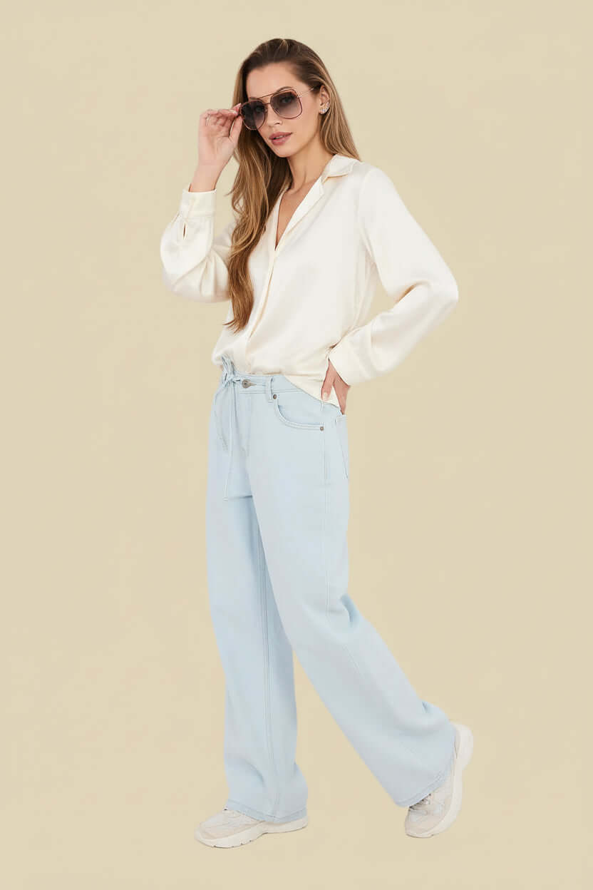  Weite Wide Leg Jeans für Damen in Hellblau kombiniert mit einem beigen Pullover für einen lockeren Freizeit-Look.