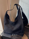 Selina - Wildlederoptik-Tasche in Schwarz auf einem Tisch mit einem Spiegel im Hintergrund.